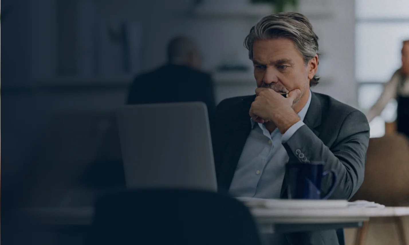 A founder reviewing his laptop in thought at his desk