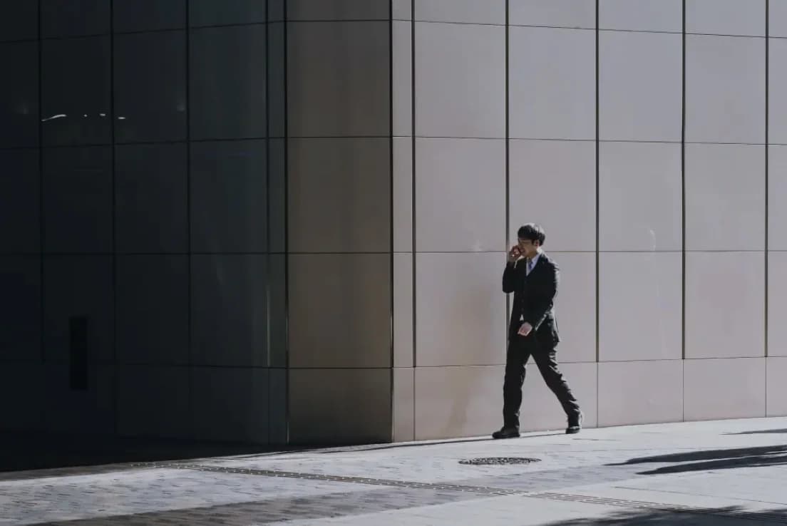 A businessman on a call walking outside an office building